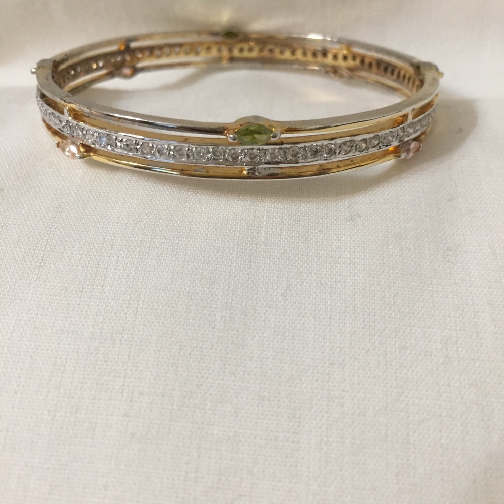 A PAIR OF GOLD TONE BRACELETS SURROUNDED BY CRYSTALS AND COLORFUL STONES